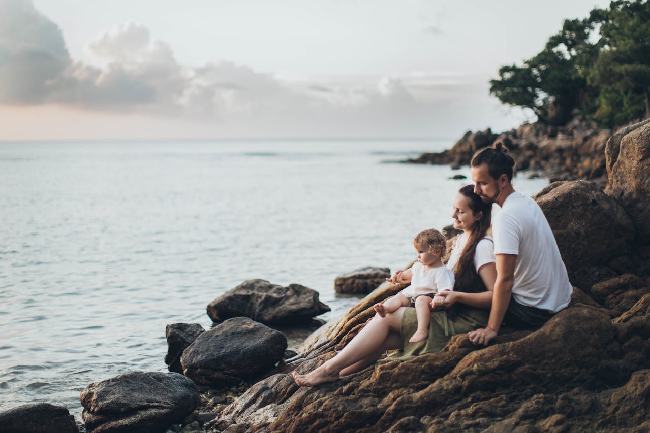 a family resting on a rock at the beach after getting their non-o family visa in thailand